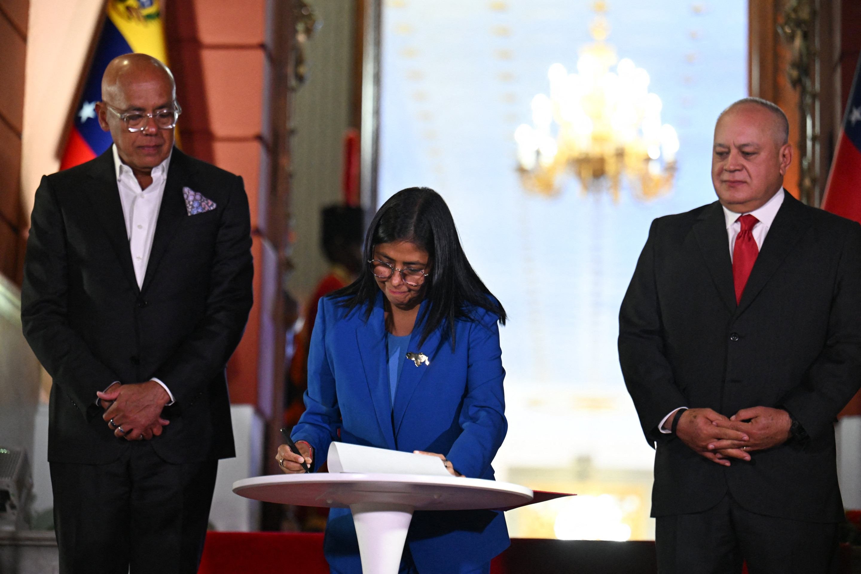 Delcy Rodr&iacute;guez (C), presidente interina da Venezuela, assina a Lei de Anistia, na noite de quinta-feira 