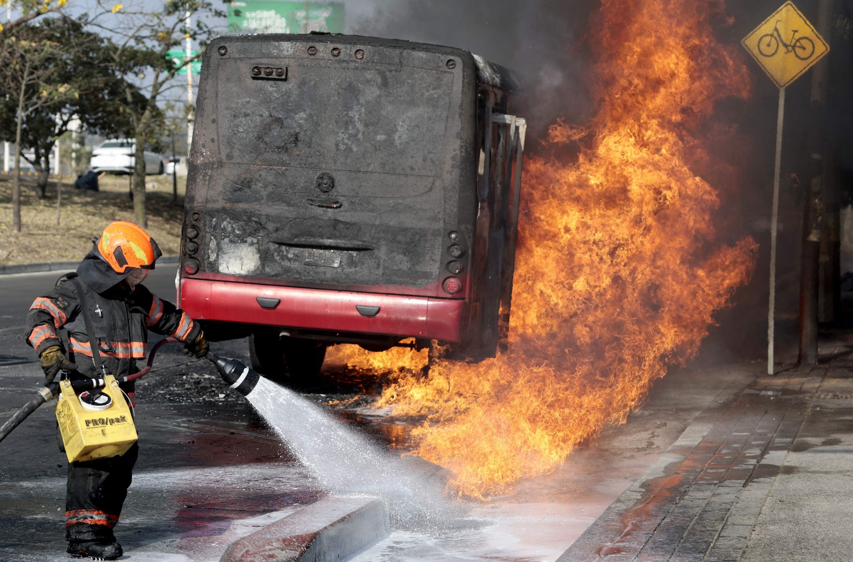  A firefighter extinguishes a burning bus set on fire by organised crime groups in response to an operation in Jalisco to arrest a high-priority security target, at one of the main avenues in Zapopan, state of Jalisco, Mexico, on February 22, 2026. Armed civilians blocked several roads in the state of Jalisco, in western Mexico, following an operation by federal forces in the town of Tapalpa, local authorities reported. Jalisco, which will host four matches of the upcoming 2026 World Cup, is home to the powerful Jalisco New Generation Cartel (CJNG), and has been rocked by several episodes of violence in recent years. (Photo by Ulises Ruiz / AFP)       