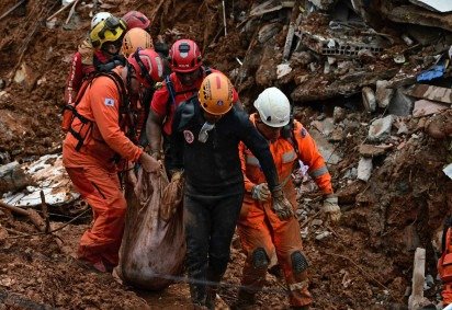 Socorristas carregam um corpo recuperado em meio aos escombros após um deslizamento de terra causado por fortes chuvas no bairro Parque Jardim Burnier, em Juiz de Fora, estado de Minas Gerais, em 24 de fevereiro de 2026       -  (crédito: PABLO PORCIUNCULA / AFP) -Socorristas carregam um corpo recuperado em meio aos escombros após um deslizamento de terra causado por fortes chuvas no bairro Parque Jardim Burnier, em Juiz de Fora, estado de Minas Gerais, em 24 de fevereiro de 2026       -  (crédito: PABLO PORCIUNCULA / AFP)