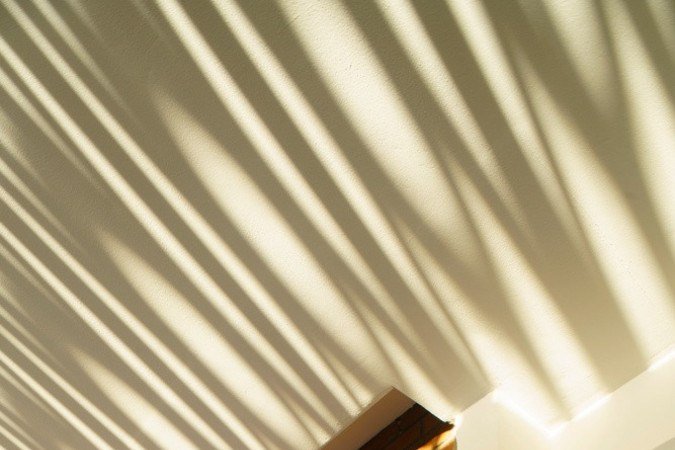 No fim da tarde, a luz atravessa os vazios e desenha padrões que aquecem visual e termicamente o interior