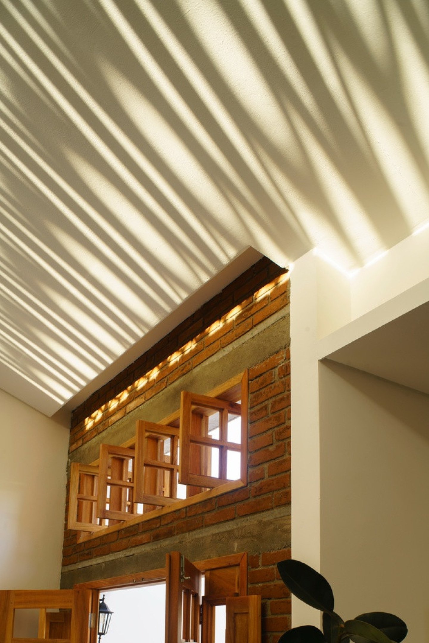 No fim da tarde, a luz atravessa os vazios e desenha padr&otilde;es que aquecem visual e termicamente o interior