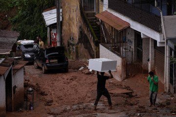 Morador carrega móvel na cabeça em rua enlameada de Juiz de Fora (MG), cidade atormentada pelas chuvas fortes há dias -  (crédito: Eduardo Anizelli/Folhapress)