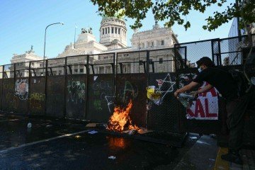 Fogo se alastra no chão durante protesto contra a reforma trabalhista em frente ao prédio do Congresso argentino -  (crédito: LUIS ROBAYO / AFP)