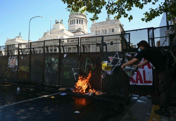 Fogo se alastra no chão durante protesto contra a reforma trabalhista em frente ao prédio do Congresso argentino -  (crédito: LUIS ROBAYO / AFP)