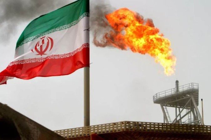 Tocha de gás em uma plataforma de produção de petróleo é vista ao lado de uma bandeira iraniana no Golfo Pérsico, única saída ao mar aberto - (crédito: Raheb Homavandi/File Photo/Reuters) Tocha de gás em uma plataforma de produção de petróleo é vista ao lado de uma bandeira iraniana no Golfo Pérsico, única saída ao mar aberto - (crédito: Raheb Homavandi/File Photo/Reuters)