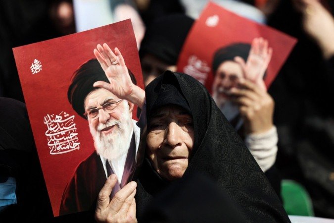 Do lado de fora da mesquita Mosalla, tamb&eacute;m em Teer&atilde;, idosa segura cartaz com a foto de Khamenei 