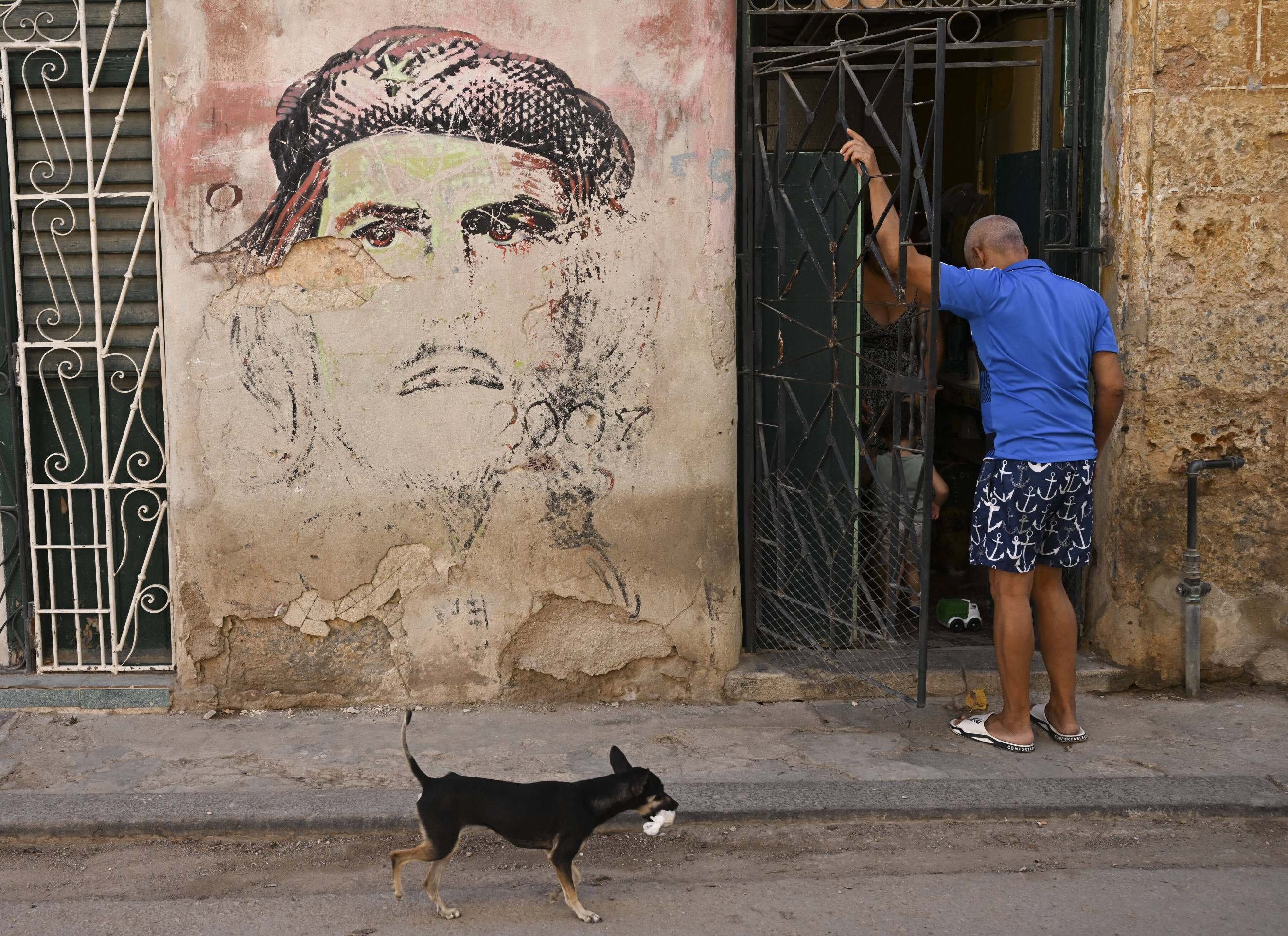 Morador de Havana na porta de casa, com a figura de Ernesto "Che" Guevara pintada na parede
