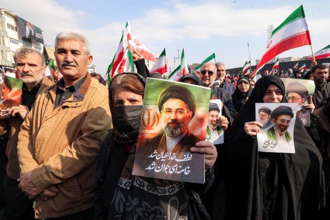 Mulheres com fotos de Mojtaba Khamenei na Praça Enghelab, em Teerã 