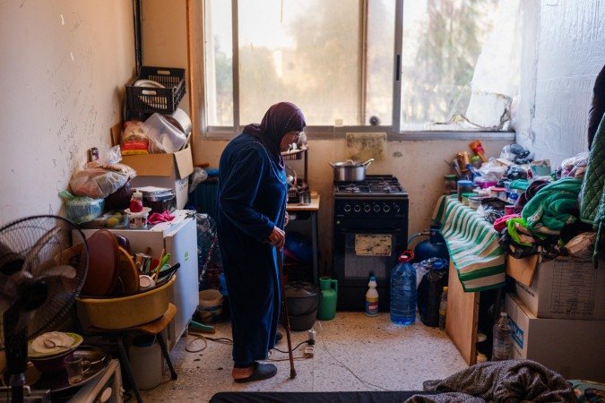 Idosa desabrigada caminha por quarto improvisado em escola usada como abrigo, na mesma cidade 