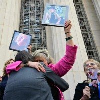Familiares de vítimas, incluindo Lori Schott (C), celebram diante do tribunal, com fotos de seus entes queridos  -  (crédito: Frederic J. Brown/AFP)