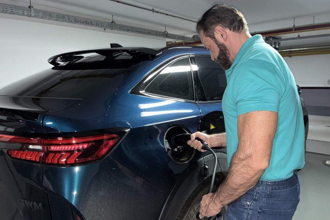 Abdias Aires recarregando seu carro no estacionamento do prédio