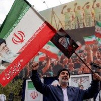 Homem segura uma bandeira iraniana com os rostos de Ali e Mojtaba Khamenei -  (crédito:  AFP)