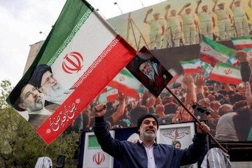 Homem segura uma bandeira iraniana com os rostos de Ali e Mojtaba Khamenei -  (crédito:  AFP)