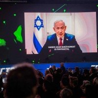 Participantes assistem e ouvem uma mensagem em vídeo do primeiro-ministro israelense Benjamin Netanyahu, exibida em um telão durante a Conferência de Ação Política Conservadora em Budapeste, Hungria, em 21 de março de 2026 -  (crédito: GERGELY BESENYEI / AFP)