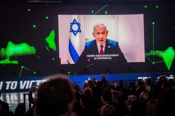 Participantes assistem e ouvem uma mensagem em vídeo do primeiro-ministro israelense Benjamin Netanyahu, exibida em um telão durante a Conferência de Ação Política Conservadora em Budapeste, Hungria, em 21 de março de 2026 - (crédito: GERGELY BESENYEI / AFP) Participantes assistem e ouvem uma mensagem em vídeo do primeiro-ministro israelense Benjamin Netanyahu, exibida em um telão durante a Conferência de Ação Política Conservadora em Budapeste, Hungria, em 21 de março de 2026 - (crédito: GERGELY BESENYEI / AFP)