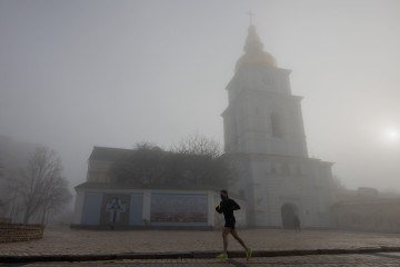Um morador local corre perto do Mosteiro de São Miguel das Cúpulas Douradas em uma manhã de neblina em Kiev, em 13 de abril de 2026, em meio à invasão russa da Ucrânia       -  (crédito: TETIANA DZHAFAROVA / AFP)