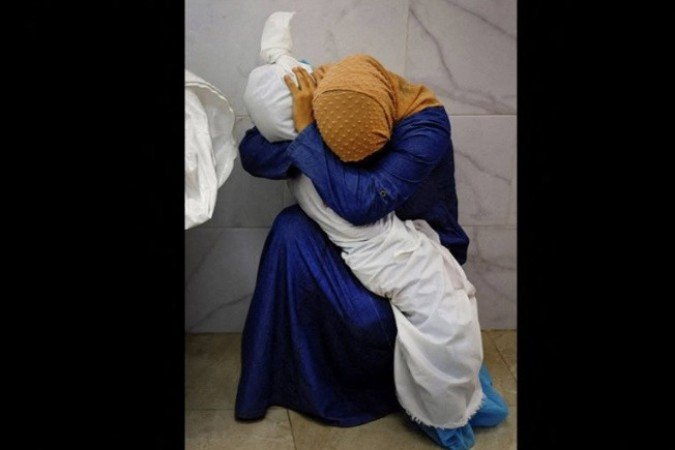 Inas Abu Maamar segura o corpo da sobrinha Saly, morta em bombardeio israelense, em 2023 