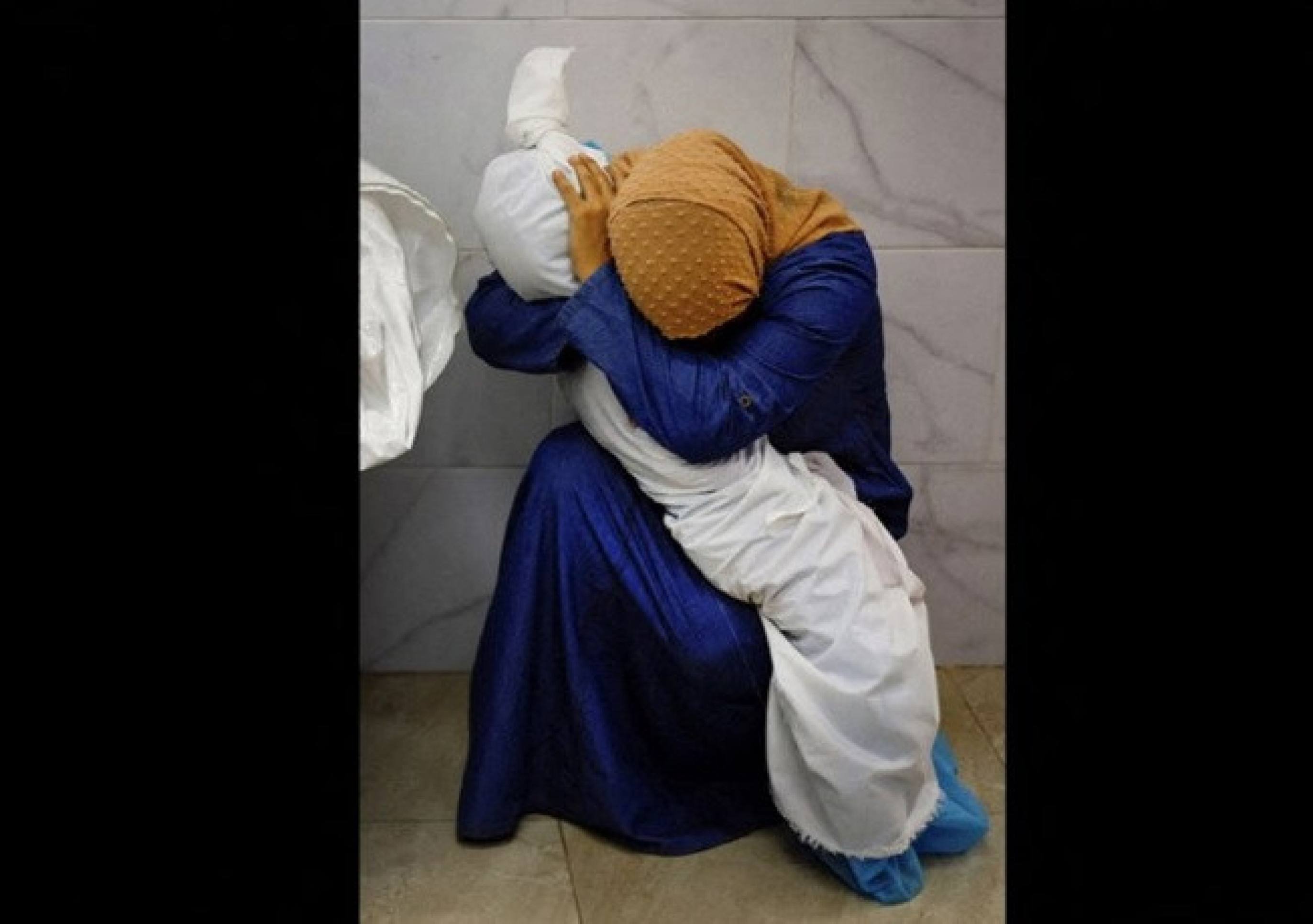 Inas Abu Maamar segura o corpo da sobrinha Saly, morta em bombardeio israelense, em 2023 