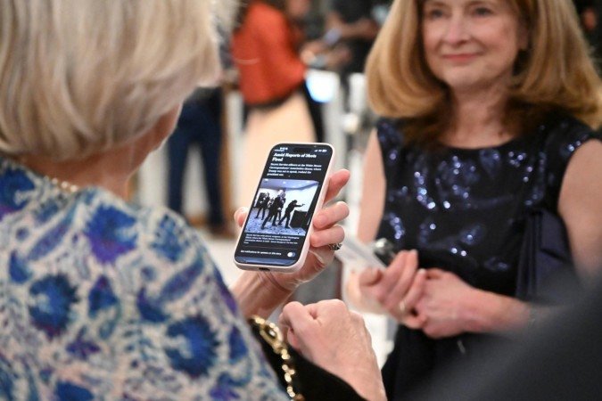  An attendee checks her phone in the lobby of the Washington Hilton after shots were heard during the White House Correspondents' Dinner in Washington, DC, on April 25, 2026. Shots were fired as US President Donald Trump attended a press dinner in Washington on April 25 night, witnesses and AFP reporters confirmed. Loud bangs were heard and guests at the black-tie White House Correspondents' Dinner scrambled to hide under tables. Tactical teams with guns drawn took position on the stage where Trump had been sitting before he was evacuated. (Photo by Alex WROBLEWSKI / AFP)
      