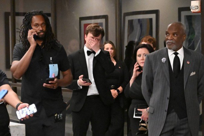  Attendees check their phones in the lobby of the Washington Hilton after shots were heard during the White House Correspondents' Dinner in Washington, DC, on April 25, 2026. Shots were fired as US President Donald Trump attended a press dinner in Washington on April 25 night, witnesses and AFP reporters confirmed. Loud bangs were heard and guests at the black-tie White House Correspondents' Dinner scrambled to hide under tables. Tactical teams with guns drawn took position on the stage where Trump had been sitting before he was evacuated. (Photo by Alex WROBLEWSKI / AFP)
      