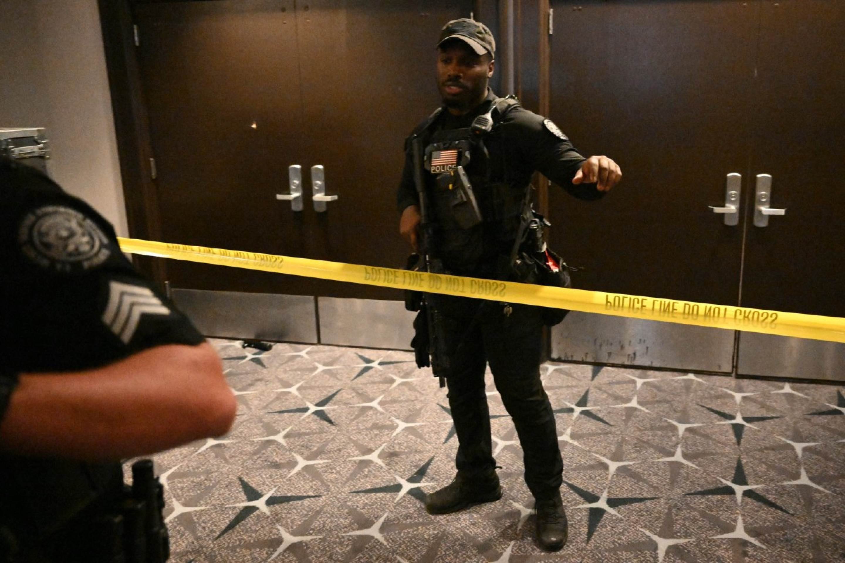 An armed police officer gestures behind police tape after shots were reportedly fired during the White House Correspondents' dinner at the Washington Hilton in Washington, DC, on April 25, 2026. Shots were allegedly fired as US President Donald Trump attended a press dinner in Washington on Saturday night, witnesses and AFP reporters said as loud bangs were heard at the hotel venue. (Photo by Mandel NGAN / AFP)
      Caption 