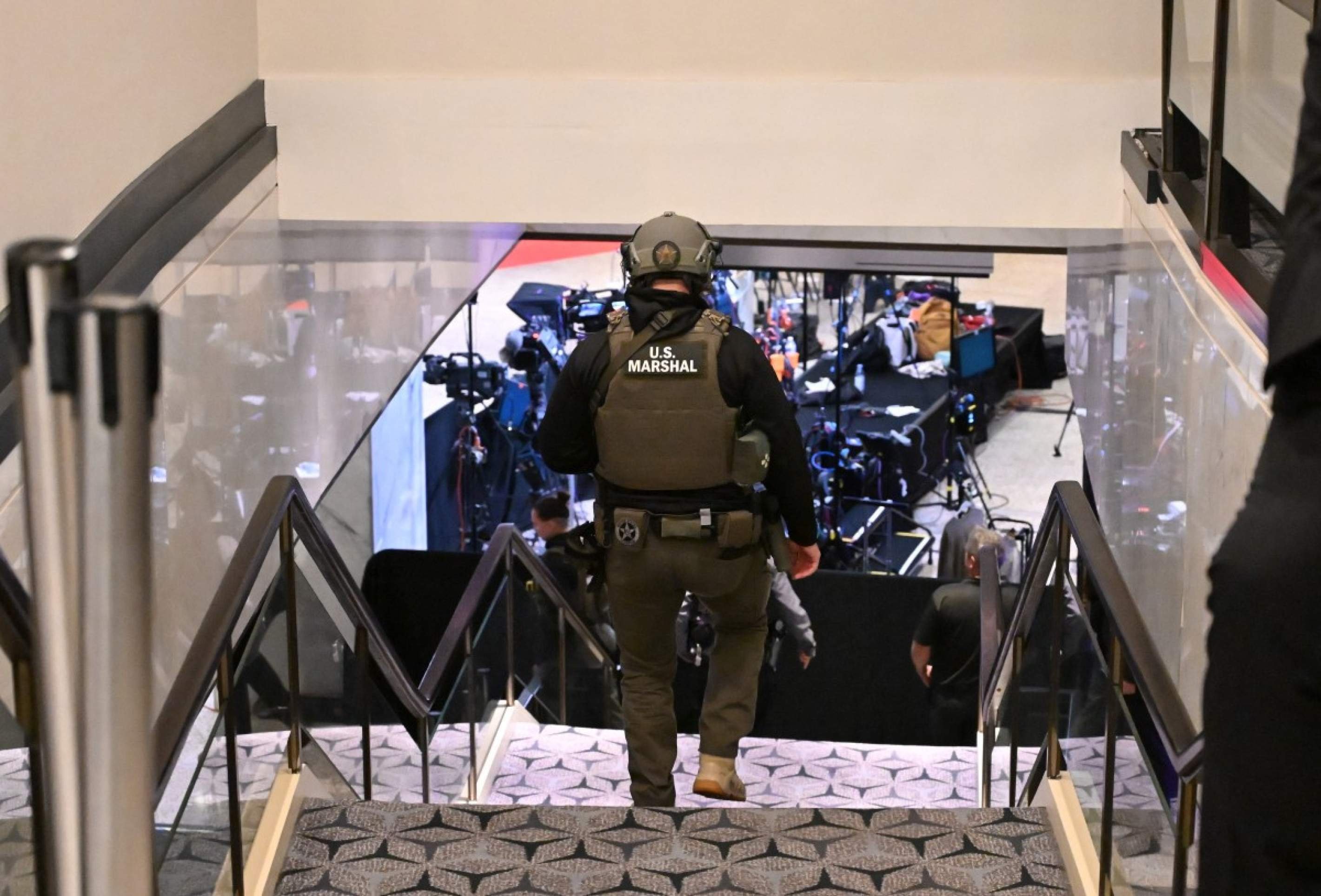  A US Marshall walks through the lobby of the Washington Hilton after shots were heard during the White House Correspondents' Dinner in Washington, DC, on April 25, 2026. Shots were fired as US President Donald Trump attended a press dinner in Washington on April 25 night, witnesses and AFP reporters confirmed. Loud bangs were heard and guests at the black-tie White House Correspondents' Dinner scrambled to hide under tables. Tactical teams with guns drawn took position on the stage where Trump had been sitting before he was evacuated. (Photo by Alex WROBLEWSKI / AFP)
      