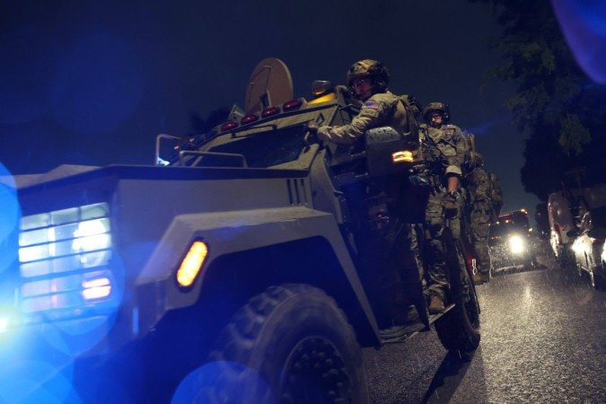 Agentes do FBI em uniformes táticos saem de casa do suspeito