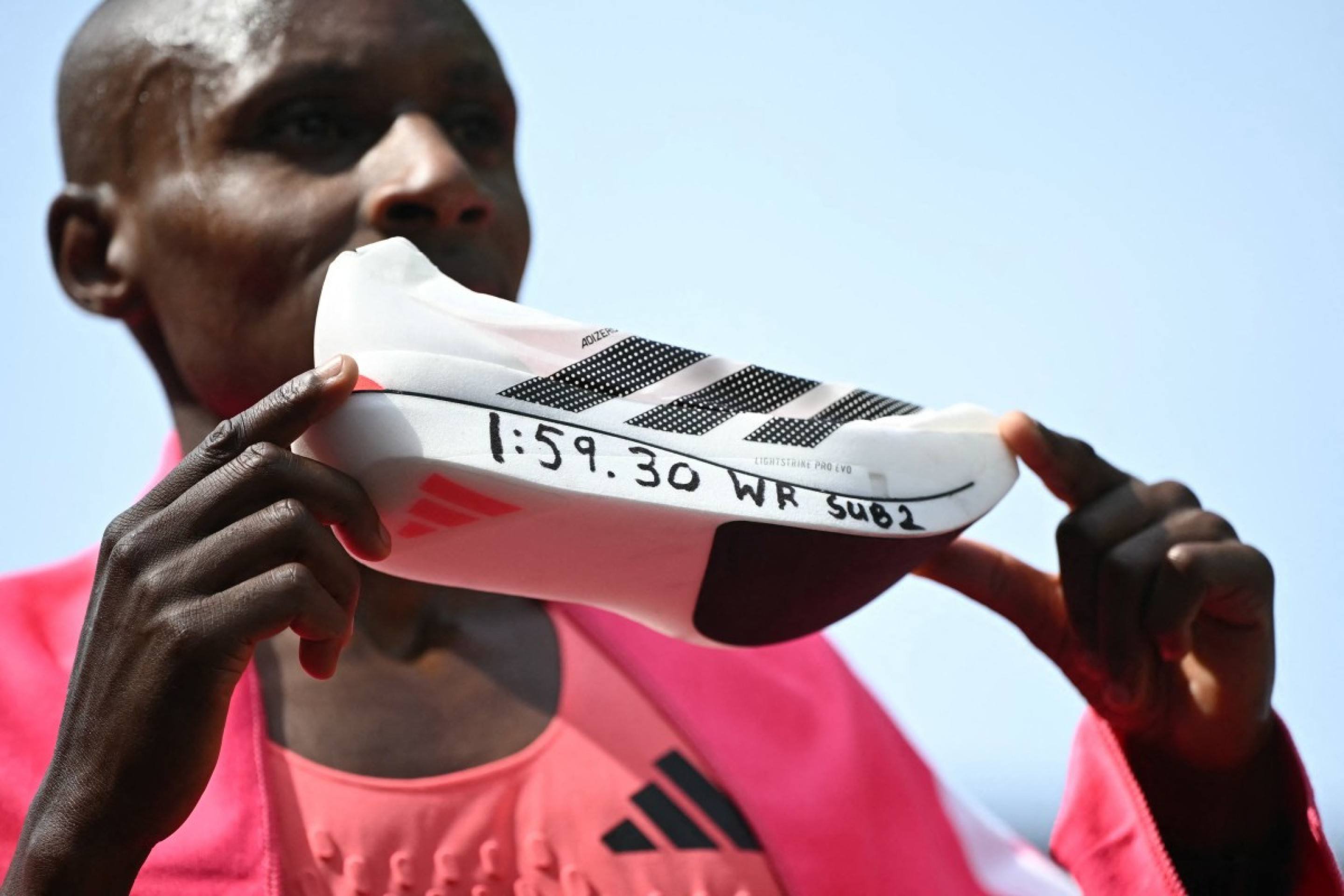  Kenya's Sabastian Sawe poses with his new world record time written on his running shoe at the finish of the 2026 London Marathon in central London on April 26, 2026. Kenya's Sabastian Sawe broke the two-hour mark for the first time in history on Sunday in winning the London Marathon. (Photo by JUSTIN TALLIS / AFP) / ?Restricted to editorial use - sponsorship of content subject to LMEL agreement?.        