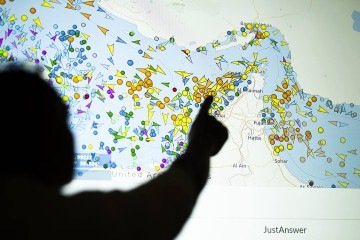 Uma foto ilustrativa tirada em Nicósia em 4 de maio de 2026 mostra uma pessoa em frente a uma grande tela exibindo os movimentos de embarcações no Estreito de Ormuz em um site de rastreamento de navios       -  (crédito:  AFP)