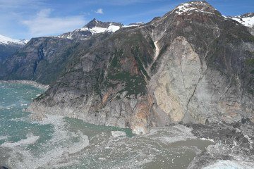 Vista ao nível do solo dos danos causados ??pelo tsunami perto da foz do fiorde, mostrando árvores arrancadas e vegetação removida da costa -  (crédito: BBC)