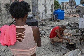 Em Havana, pessoas caminham ao lado de uma grande lixeira incendiada na noite anterior em protesto contra os prolongados apagões -  (crédito: EPA/Shutterstock)