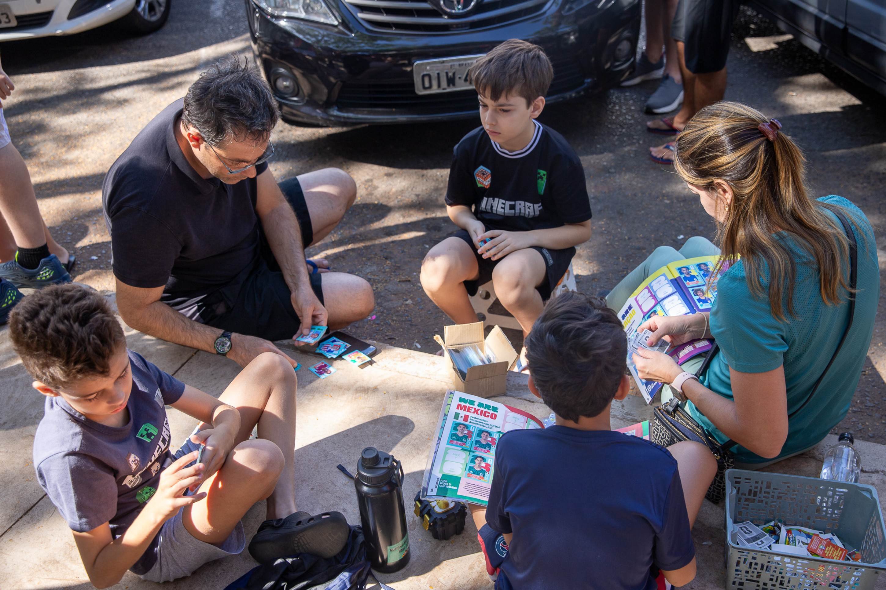 Troca feita, &eacute; hora de colar no &aacute;lbum, ali mesmo, sentado na cal&ccedil;ada  