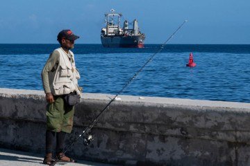 Do Malecón, pescador observa navio panamenho Asian Katra chegando a Havana com ajuda humanitária proveniente do governo mexicano -  (crédito: Yamil Lage/AFP)
