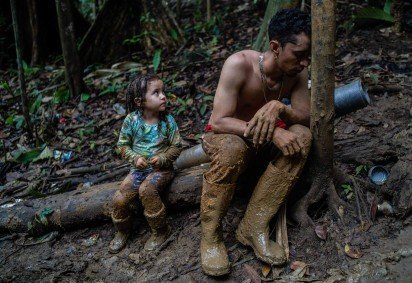 O imigrante venezuelano Luis Miguel Arias, de 28 anos descansa ao lado da filha Melissa, 4, enquanto sobe uma colina na região do Darién, entre a Colômbia e o Panamá. Luis Miguel atravessou o Darién com seus dois filhos, sua esposa e um amigo      -  (crédito: Federico Rios Escobar)