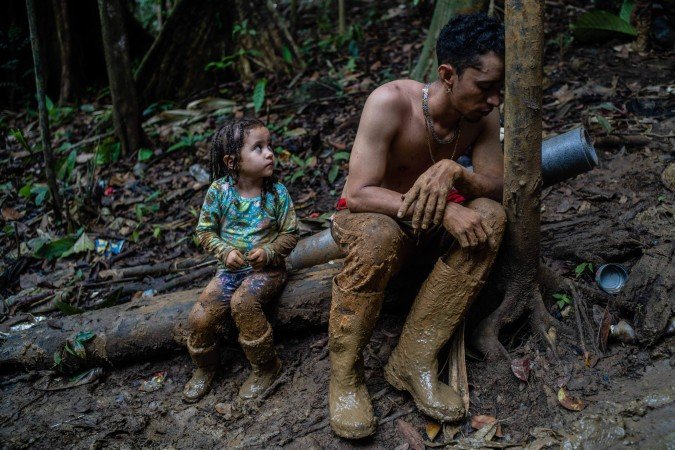 O imigrante venezuelano Luis Miguel Arias, de 28 anos descansa ao lado da filha Melissa, 4, enquanto sobe uma colina na região do Darién, entre a Colômbia e o Panamá. Luis Miguel atravessou o Darién com seus dois filhos, sua esposa e um amigo      -  (crédito: Federico Rios Escobar)