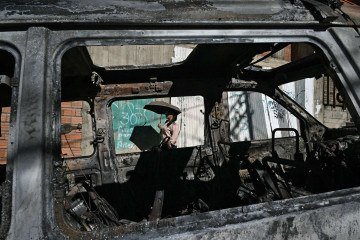 Moradora caminha ao lado de viatura policial incediada durante manifestações, em La Paz  -  (crédito: Aizar Raldes/AFP)