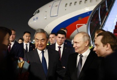 Putin (C) é recebido no aeroporto pelo chanceler Wang Yi: 