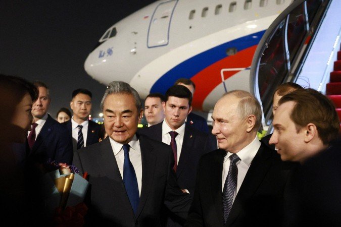 Putin (C) é recebido no aeroporto pelo chanceler Wang Yi: Putin (C) é recebido no aeroporto pelo chanceler Wang Yi:
