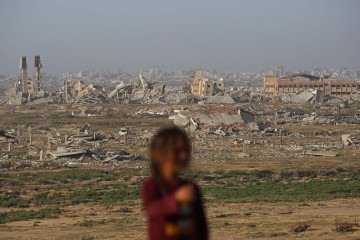 Menina palestina diante de edifícios destruídos em Deir al-Balah, no centro da Faixa de Gaza -  (crédito: Eyad Baba/AFP)