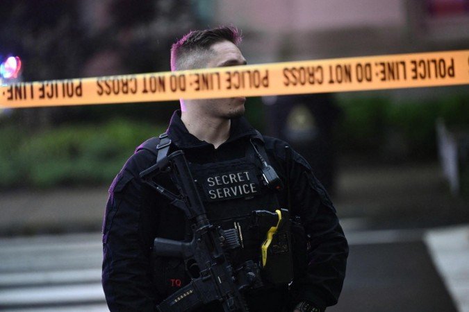  An armed secret service police officer stands behing tape blocking off a crime scene near the White House in Washington, DC, on May 23, 2026. Police and security forces swarmed the area around the White House on the evening of May 23 after reports of shots fired, AFP journalists said. US President Donald Trump was at the White House at the time as he worked to negotiate a deal with Iran. (Photo by Brendan SMIALOWSKI / AFP)
      
