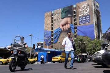 Moradores de Teerã passam por mural em fachada de prédio com a legenda em farsi 'Sempre nas mãos do Irã', em alusão ao Estreito de Ormuz   -  (crédito: Atta Kenare/AFP)