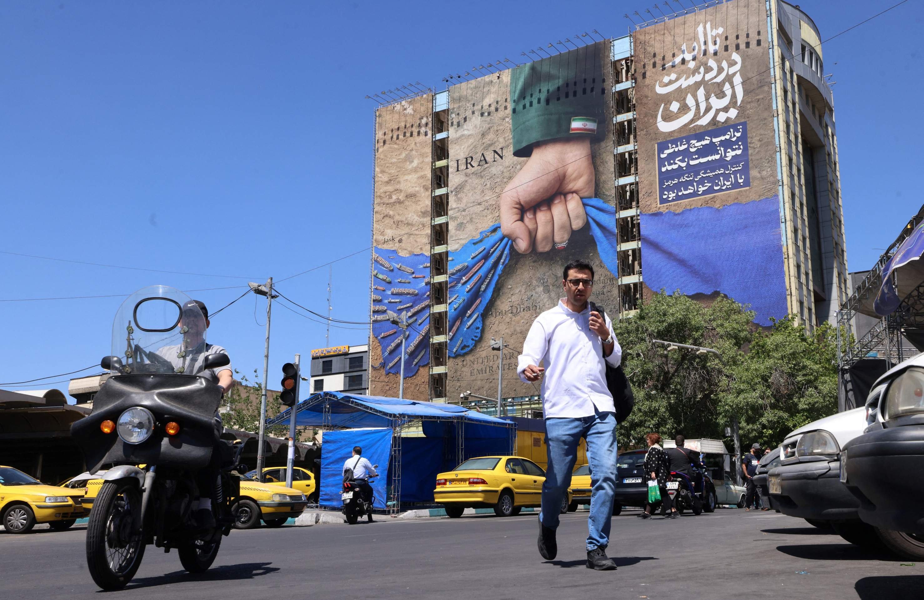 Moradores de Teerã passam por mural em fachada de prédio com a legenda em farsi 'Sempre nas mãos do Irã', em alusão ao Estreito de Ormuz   -  (crédito: Atta Kenare/AFP)