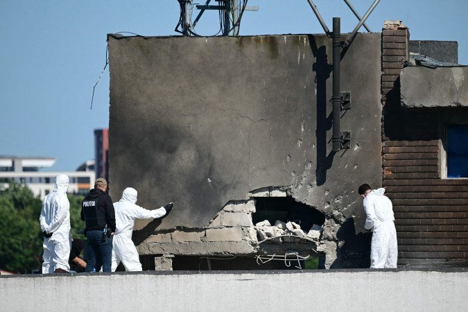 A polícia e peritos forenses examinam o local do impacto após um drone russo atingir um prédio de apartamentos em Galati, no leste da Romênia. Um drone russo feriu duas pessoas ao atingir um prédio de apartamentos na Romênia, membro da OTAN, informou o Ministério da Defesa do país em 29 de maio de 2026 - (crédito: DANIEL MIHAILESCU / AFP) A polícia e peritos forenses examinam o local do impacto após um drone russo atingir um prédio de apartamentos em Galati, no leste da Romênia. Um drone russo feriu duas pessoas ao atingir um prédio de apartamentos na Romênia, membro da OTAN, informou o Ministério da Defesa do país em 29 de maio de 2026 - (crédito: DANIEL MIHAILESCU / AFP)