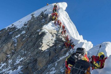 Esta fotografia, tirada em 20 de maio de 2026, mostra alpinistas escalando uma encosta, alinhados durante a ascensão do Degrau Hillary até o cume do Monte Everest, no Nepal       -  (crédito: FURTE SHERPA / AFP)