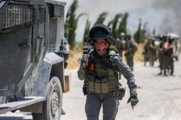 Um membro das forças de segurança israelenses passa por um veículo blindado enquanto dispersam palestinos que se reuniram ao longo de uma estrada para protestar contra a suposta queima de suas terras por colonos israelenses na vila palestina de Idna, a oeste de Hebron, na Cisjordânia ocupada, em 5 de junho de 2026 - (crédito: HAZEM BADER / AFP) Um membro das forças de segurança israelenses passa por um veículo blindado enquanto dispersam palestinos que se reuniram ao longo de uma estrada para protestar contra a suposta queima de suas terras por colonos israelenses na vila palestina de Idna, a oeste de Hebron, na Cisjordânia ocupada, em 5 de junho de 2026 - (crédito: HAZEM BADER / AFP)
