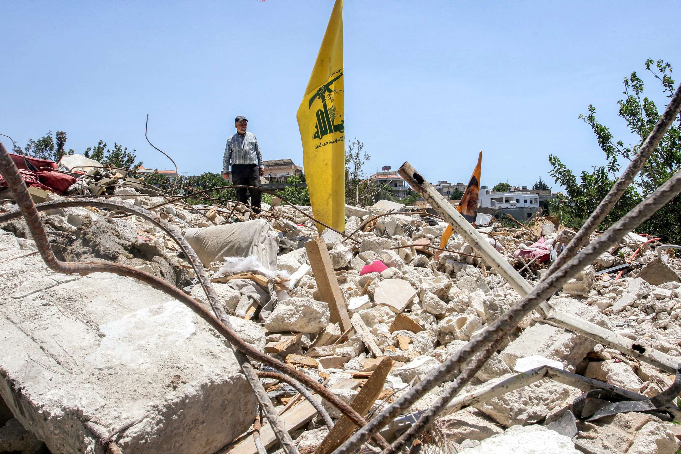 Ali Hassan Najdi, 64 anos, observa bandeira do Hezbollah sobre escombros da cada do primo, no sul do L&iacute;bano