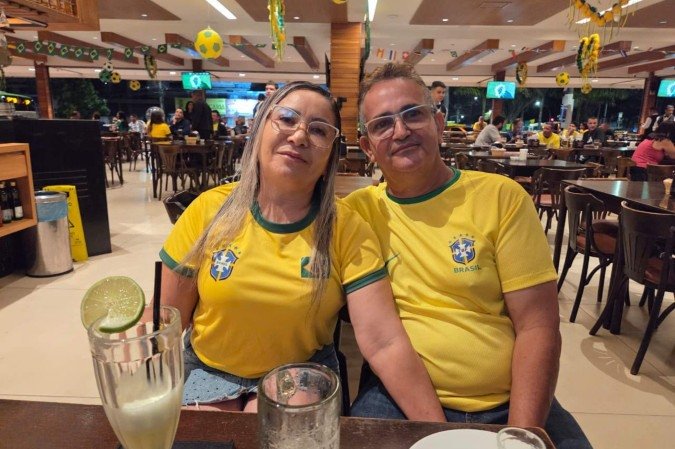 Entre as centenas de mesas, Genildo de Alves, 55 anos, e a mulher, Maria José, 52, escolheram um lugar estratégico para ver a partida: uma mesa bem em frente a uma das 40 TVs instaladas nos salões. 