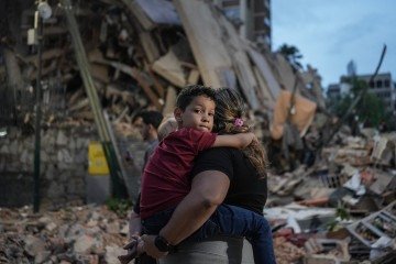 Pessoas passam por um prédio que desabou após um terremoto em Caracas, em 25 de junho de 2026. -  (crédito:  AFP)