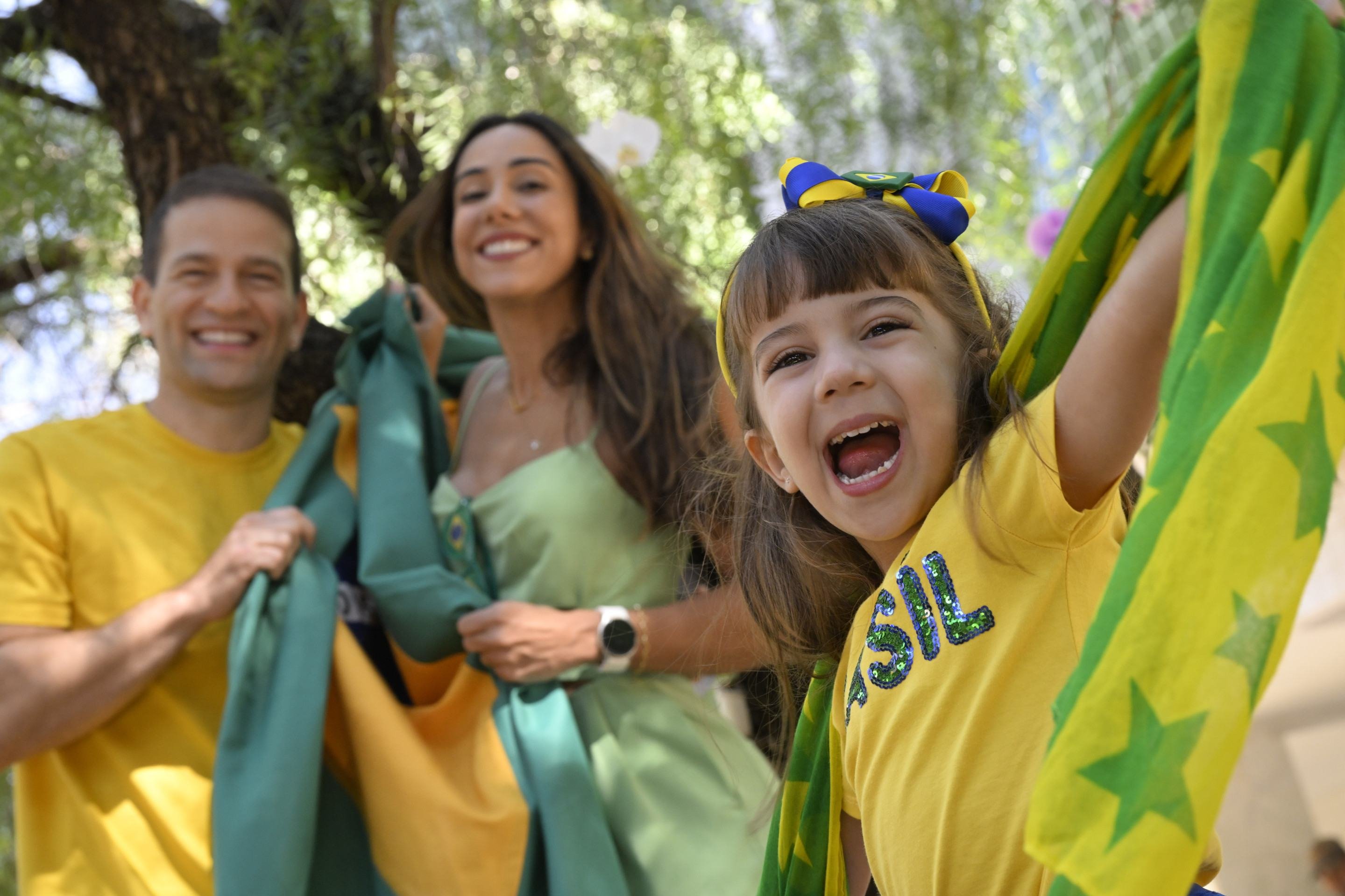 Laurinha, na foto com os pais Nat&aacute;lia e Mac, ama o aspecto festivo da Copa