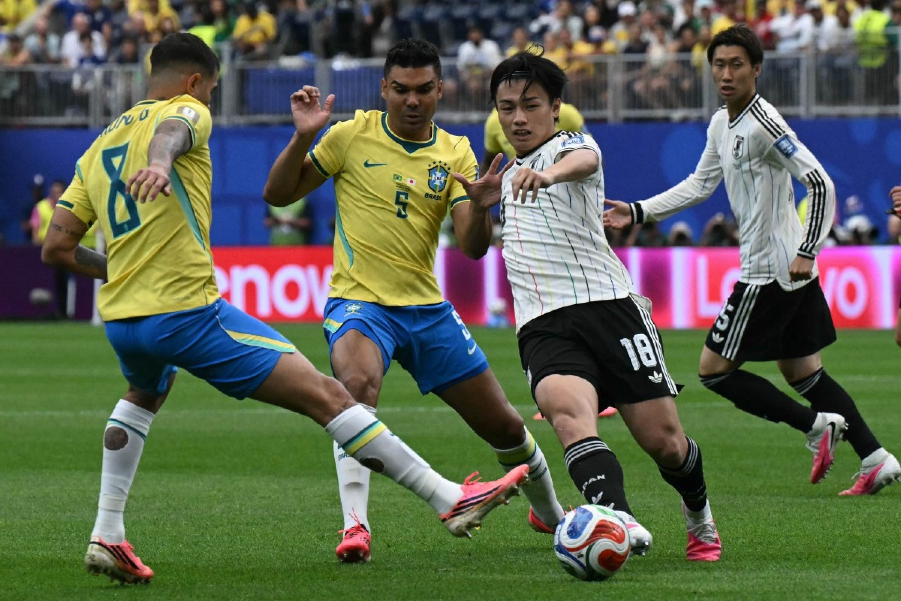 O meio-campista brasileiro n&ordm; 8 Bruno Guimar&atilde;es (&agrave; esq.) e o meio-campista brasileiro n&ordm; 5 Casemiro (ao centro) disputam a bola com o atacante japon&ecirc;s n&ordm; 18 Ayase Ueda (2&ordm; &agrave; dir.) no Houston Stadium, em Houston, em 29 de junho